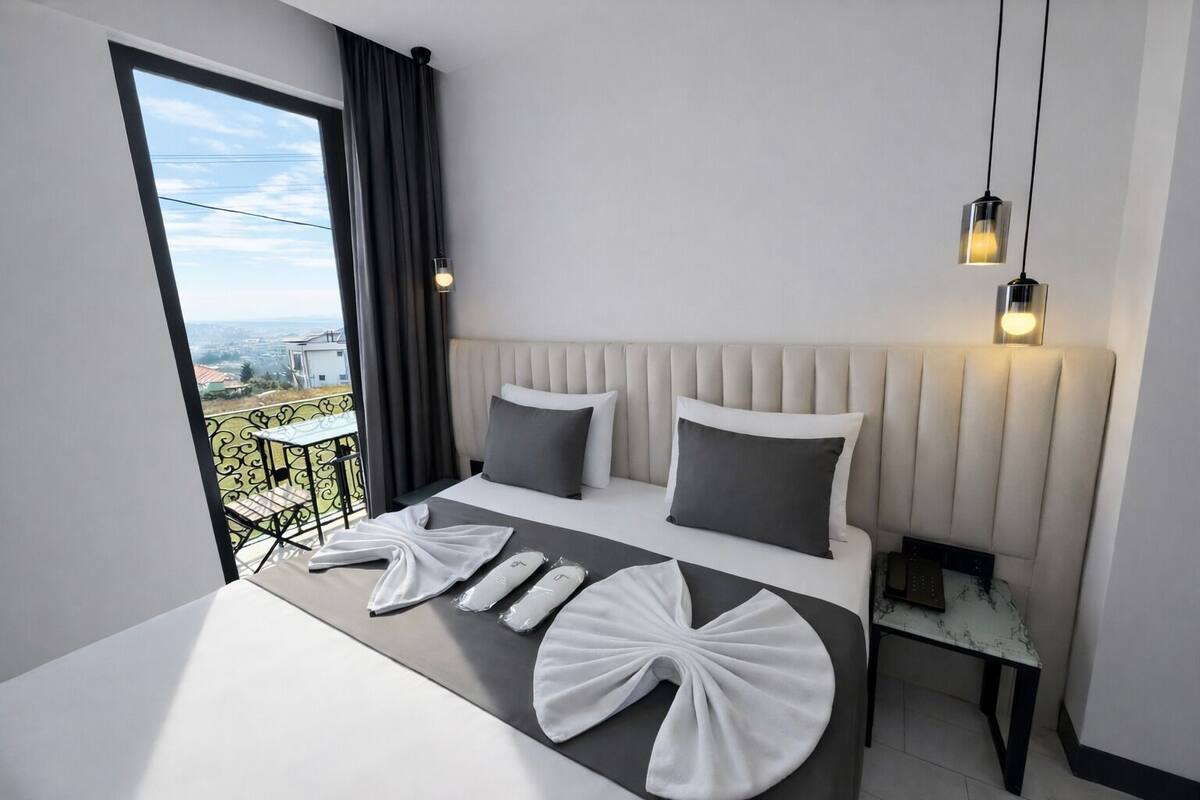 Una habitación de hotel moderna con una cama grande, un balcón con vistas y una mesita.