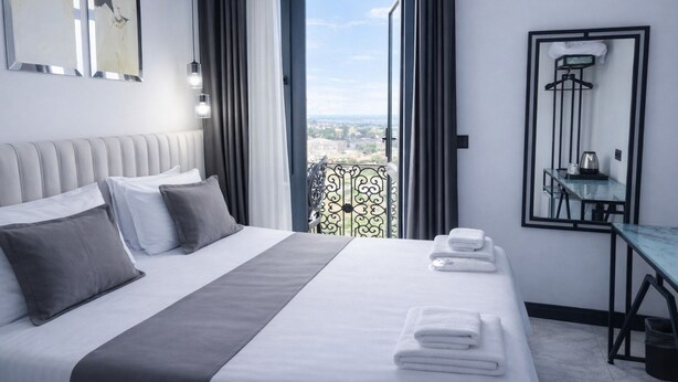 Une chambre d’hôtel avec un lit, un balcon, une table et un miroir.