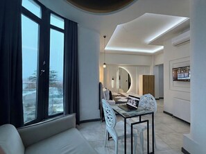 A modern living room with a sofa, a dining table with chairs, and a laptop. - D Twins plus Hotel (Arnavutköy)