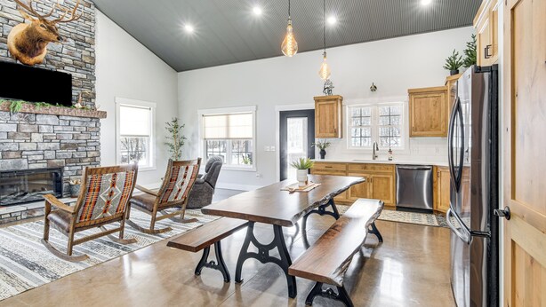 Une cuisine spacieuse avec une cheminée en pierre, des armoires en bois et une grande table à manger.