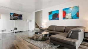 Una sala de estar moderna con un sofá gris, una mesa redonda de centro y pinturas abstractas en la pared.