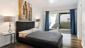 Un dormitorio moderno con cama, lámparas de noche y un cuadro en la pared.