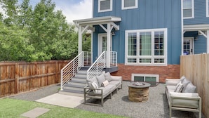 A blue two-story house with a covered patio, outdoor seating area, and a wooden fence.