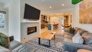 A modern living room with a fireplace, a large flat-screen TV, and a cozy seating area.