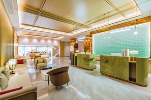 A modern hotel lobby with a reception desk, seating area, and a view of the kitchen in the background. - Dequan ShanShui Hotel (Beijing)