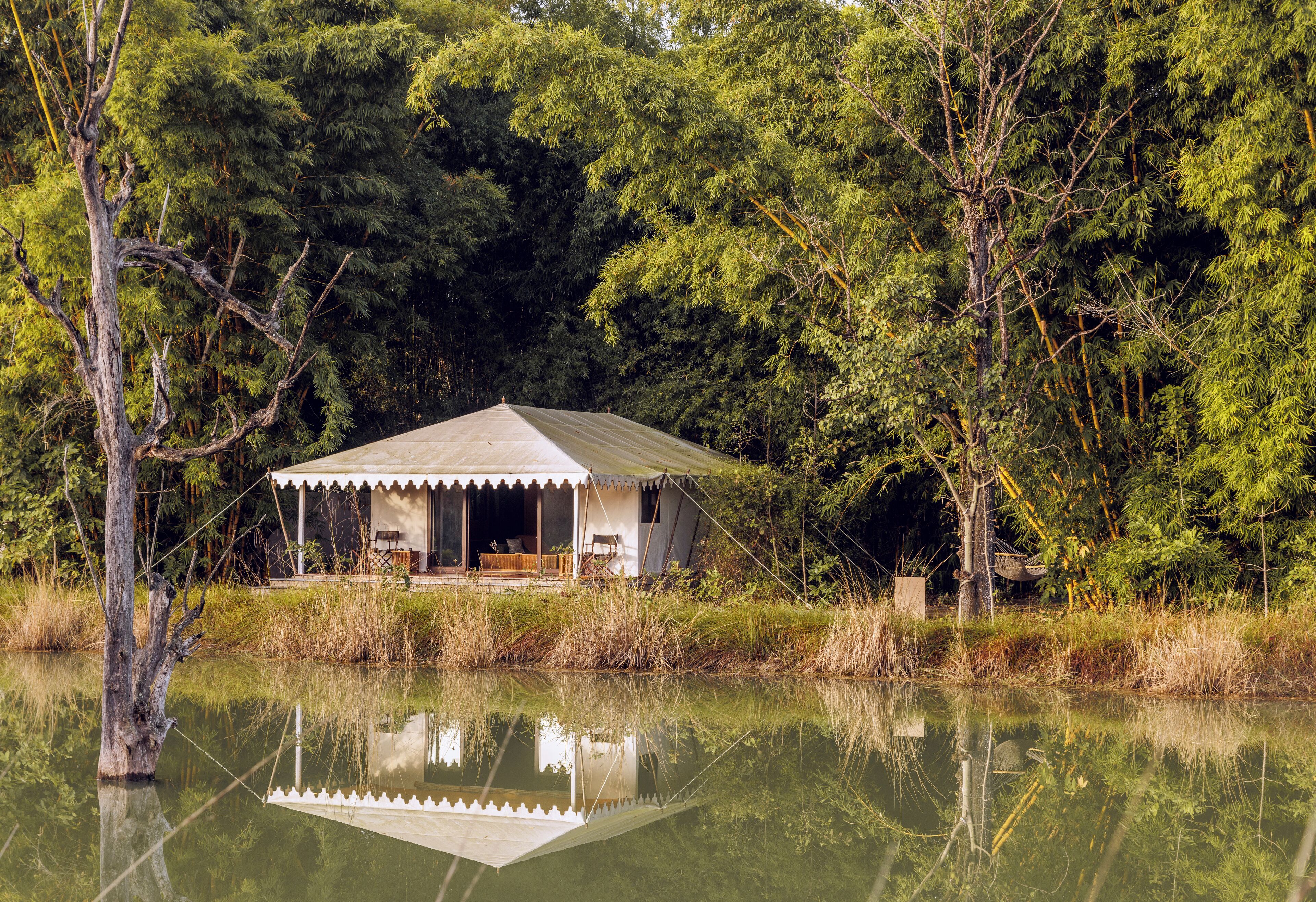 A rustic cabin by a calm lake, surrounded by dense forest.