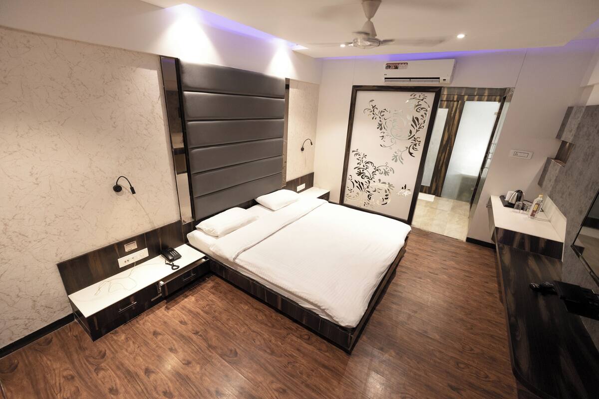 A modern bedroom with a large bed, a bedside table, a mirror, and a wardrobe.