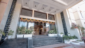 A hotel entrance with a grand staircase, large windows, and potted plants. - Hotel Vikramaditya (Ujjain)