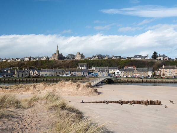 A coastal town with a prominent church, sandy beach, and a bridge connecting the shore to the town. - Harbour Nights Deluxe 7D by Interhome (Lossiemouth)