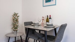 Ruokailutila, jossa on neljälle katettu pöytä. Pöydällä on kehystetty kuva, viinipulloja ja laseja.