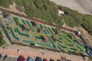 Eine Vogelperspektive eines Golfplatzes mit mehreren Grünflächen, Wegen und Holzbauten.