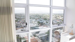 A room with large windows offering a view of a residential area. - Luxurious 3-bedroom Apartment With Ocean Views in Cape Town (Cape Town)