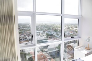 A room with large windows offering a view of a residential area.
