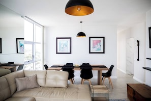 A modern living room with a sofa, dining table, and pendant lights.