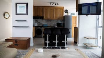 Cocina moderna con armarios de madera, microondas integrado y un televisor mostrando una programación.