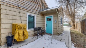 Una casa con una puerta azul, un sillón cubierto y una manguera en el porche.