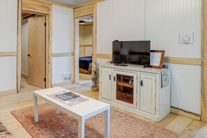 Ein Zimmer mit einem weißen Tisch, einem Fernseher auf einem Schrank und einer Tür zu einem weiteren Raum.