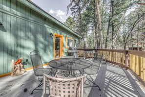 Relax on the deck with a round table and wicker chairs, surrounded by a dense forest.