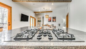 A spacious room with a long table, a fireplace, and a television on the wall. - Walk to Midtown Ruidoso: Modern-Rustic Cabin (Ruidoso)