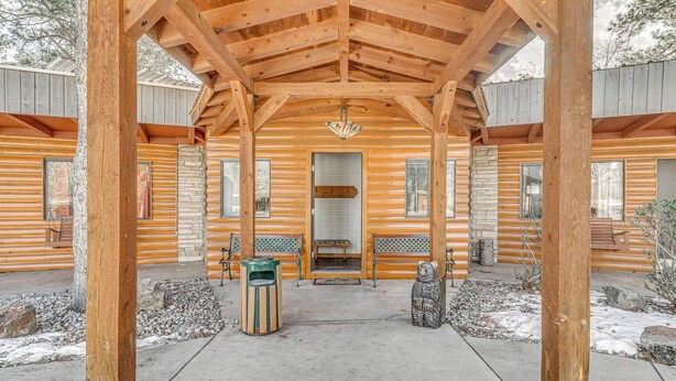 A log cabin with a covered porch, stone fireplace, and benches. - Walk to Midtown Ruidoso: Modern-Rustic Cabin (Ruidoso)