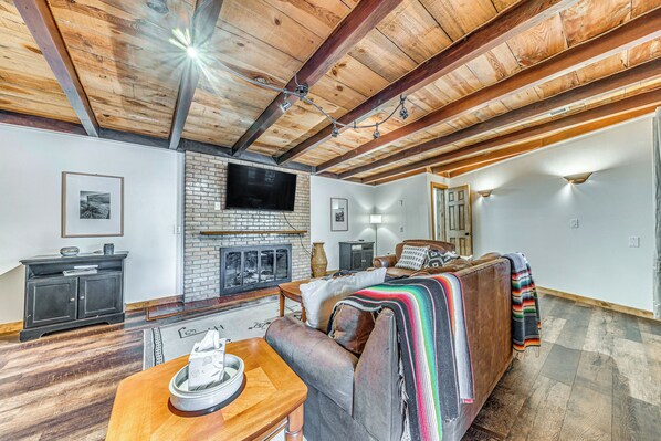 Relax in this inviting living area with a comfortable sofa, flat-screen TV, and brick fireplace.