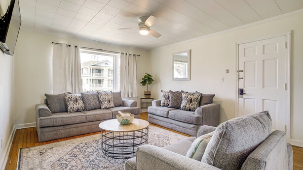 Ein Wohnzimmer mit zwei grauen Sofas, einem Couchtisch und einem Deckenventilator.