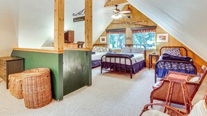 A cozy attic bedroom with two beds, a dining table, wicker baskets, and a ceiling fan. - 1 Mi to Lake Easton: Cozy Cascades Cabin! (Easton)