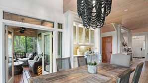 Un comedor amplio con una gran mesa de madera, mobiliario de mimbre y una lámpara colgante.