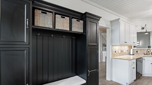 Una cocina moderna con armarios oscuros, un banco empotrado y cestas de mimbre en los estantes superiores.