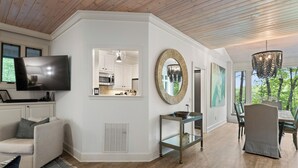 Una sala de estar moderna con televisión, sofá, mesa de comedor y sillas.