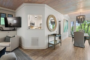 A modern living room with a television, sofa, dining table, and chairs.
