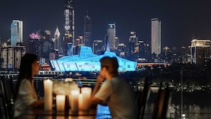Una mesa de comedor con velas y vista al horizonte urbano nocturno.