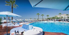 A poolside area with lounge chairs, umbrellas, and a wooden deck. - LORCRIMAR-PUERTO BANUS-MARBELLA (Unknown)
