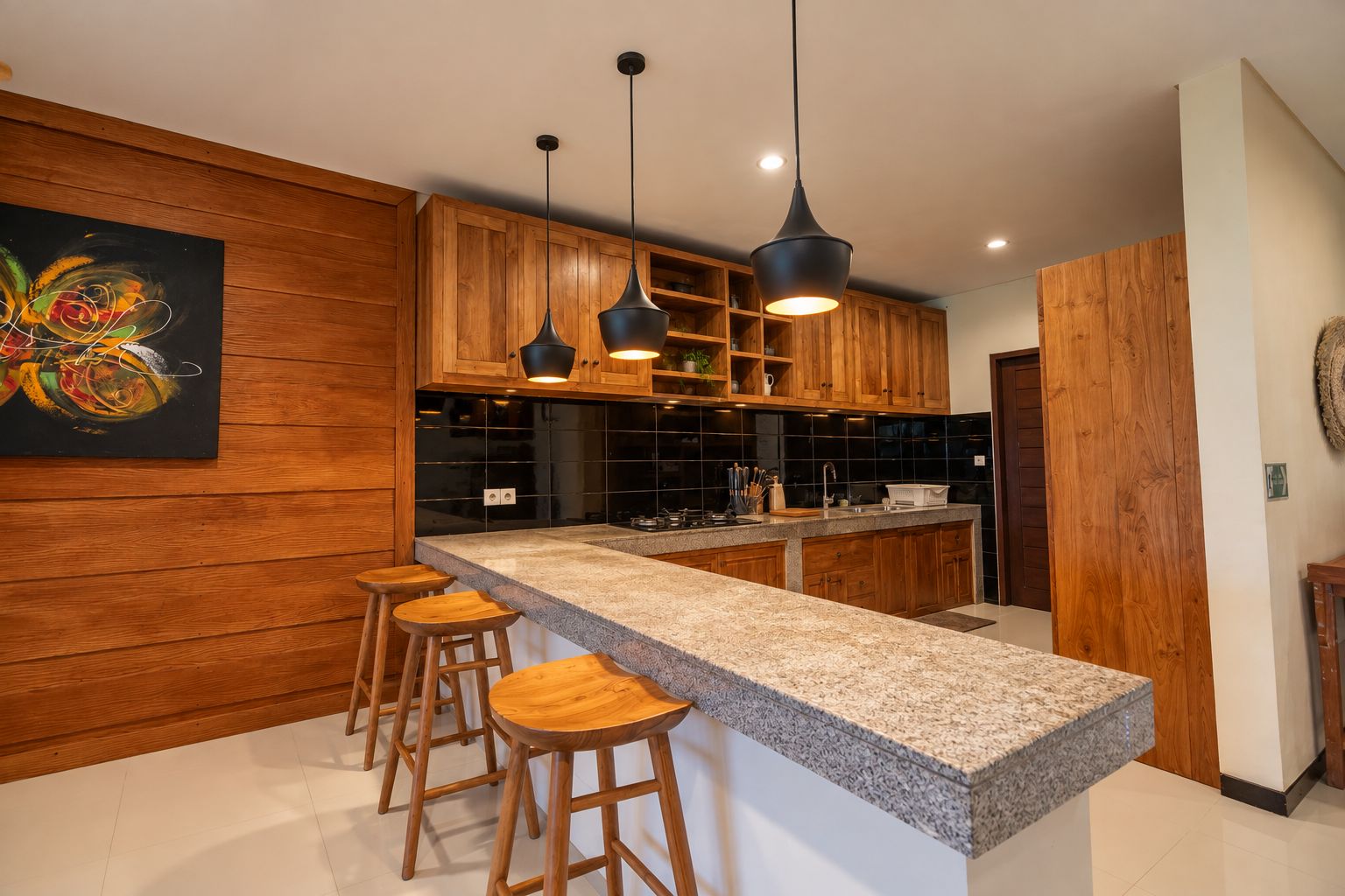 Una cocina moderna con armarios de madera, encimera de granito e iluminación colgante.