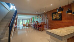 A spacious kitchen with a granite countertop, wooden cabinets, and pendant lighting. - Mardika Private Villa Ubud (Ubud)