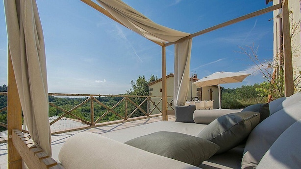 Un balcon doté d’un espace salon avec des coussins, d’une rambarde en bois et d’une vue sur le paysage.