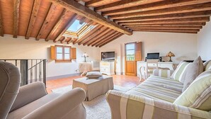Un salon spacieux avec un haut plafond en bois, un canapé, une table basse et un téléviseur.
