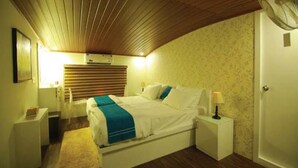 A bedroom with a bed, bedside tables, a nightstand, a fan, and a door. - Whispering Waters Houseboat (Ambalapuzha)