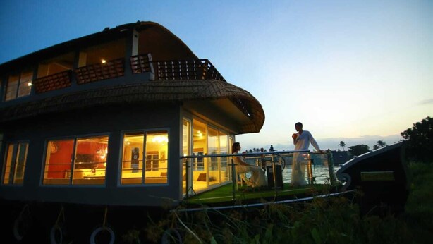 A boat with a curved roof and a balcony, featuring large windows and a grassy deck. - Whispering Waters Houseboat (Ambalapuzha)
