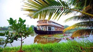 A houseboat with a balcony, surrounded by water and greenery. - Whispering Waters Houseboat (Ambalapuzha)