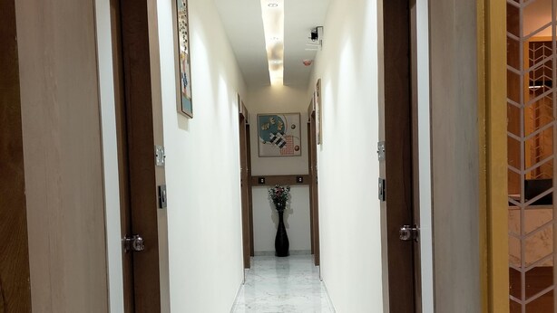 A hallway with marble flooring, wooden doors, and recessed lighting. - Hotel Paris Plaza (Ahmedabad)