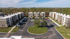 Un immeuble d’appartements moderne doté d’une cour intérieure, d’un parking et offrant une vue sur une zone résidentielle.