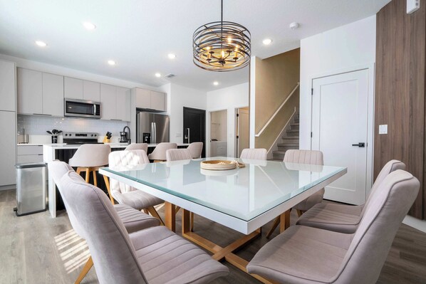 Enjoy meals in this inviting kitchen and dining area, featuring stainless steel appliances and a glass-top dining table.