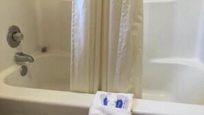 A bathtub with a white curtain, a towel, and a bottle of shampoo. - Charming Hotel in a quiet spot, next to a Walmart, located in Seminole, Texas. (Seminole)