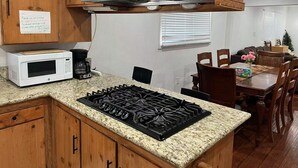 Une cuisine compacte dotée de meubles en bois, d’une hotte en acier inoxydable, d’un four à micro-ondes, d’une cuisinière à gaz et d’une machine à café.