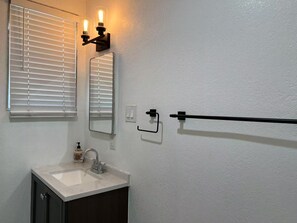 A bathroom with a white sink, two wall-mounted mirrors, and a towel rack.
