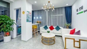 Un moderno hall de hotel con un sofá blanco, una mesa redonda para café y un comedor con sillas amarillas.