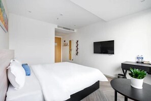 A modern hotel room with a large bed, a flat-screen TV, a desk, and a potted plant. - Shenzhen Welcome Inn (Shenzhen)