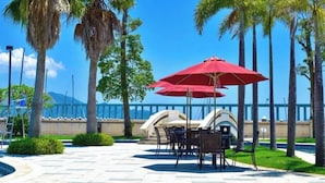 A patio with outdoor seating, palm trees, and a view of the ocean. - Huizhou Hazens East Resort (Huizhou)