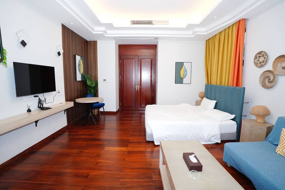 Una habitación de hotel moderna con una cama, un sofá, un televisor, un escritorio y una mesa de comedor.